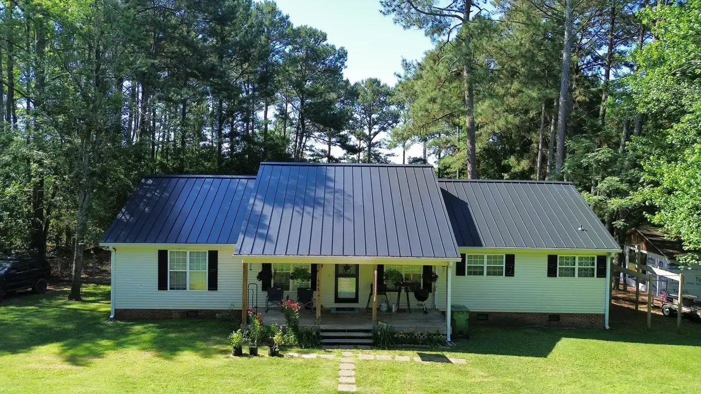 Farmhouse with a completed charcoal standing seam metal roof over the main house and front porch