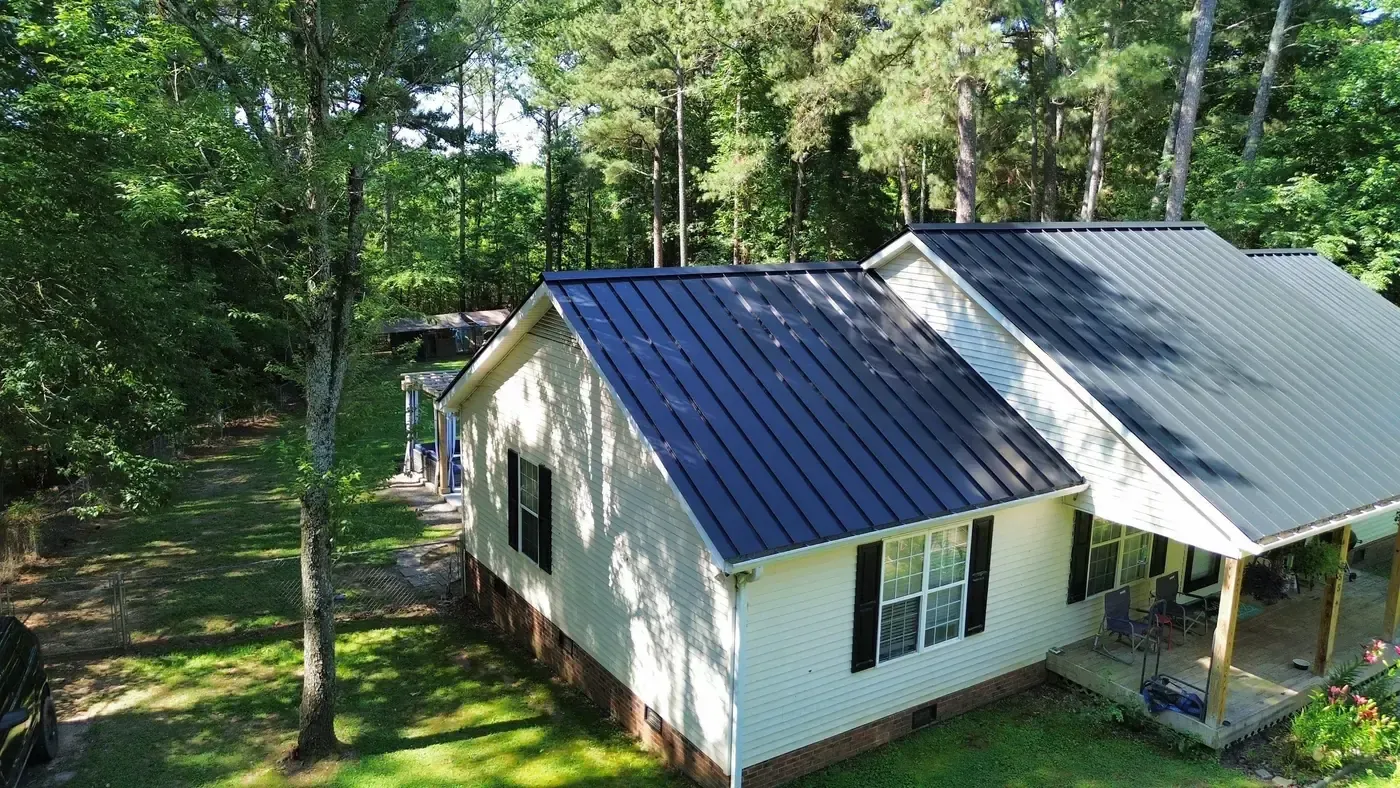 Completed charcoal standing seam metal roof on a farmhouse, seen from above at an angle