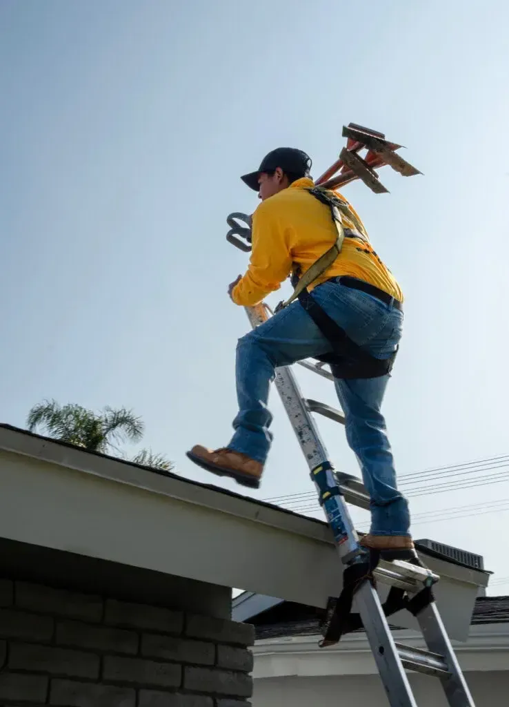 On Tops Roofing team member climbing onto a roof for an inspection