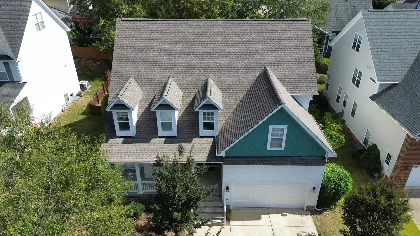 Front-facing aerial of a completed On Tops Roofing project in Cary, NC with new dark architectural shingles, dormers, and white fascia trim